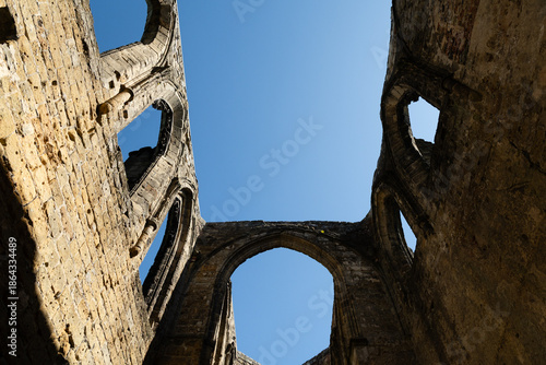 Gothic arches framing blue sky in the sunlit ruins of Oybin Monastery, part of the castle complex on Oybin mountain in Saxony, Germany