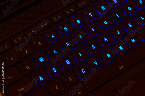 Close-up of a colorful RGB mechanical gaming keyboard illuminated in vibrant hues. Modern computer accessory designed for gaming setups, featuring customizable backlighting and sleek design. 