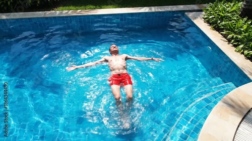 Man relaxes in swimming pool water with sunny daylight