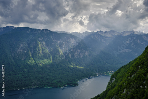 Amazing viewpoint of lake Bohinj in Triglav national park, with impressive mountain peaks in the background and sunlight on the forest
