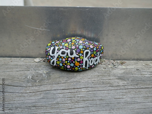 You rock kindness rock on wooden board with shiny metal background