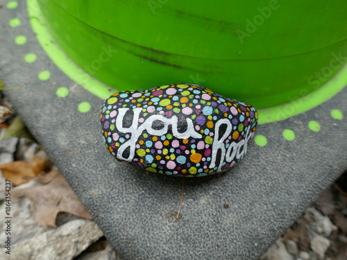 Close-up of you rock kindness rock on base of green traffic cone