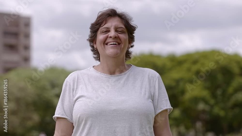 Happy middle-aged woman laughing outdoors in a park setting