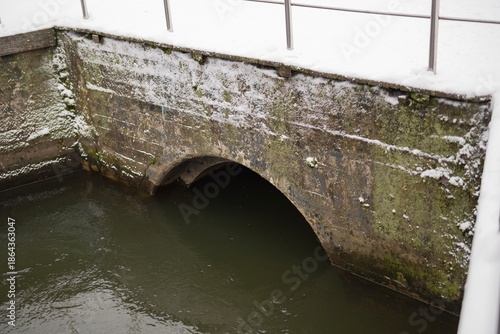 Round hole with a pipe in a concrete bridge for water drainage during winter. Urban infrastructure and engineering detail