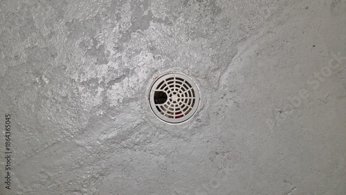 Drain hole in a concrete floor at an indoor location showing signs of wear and usage with surrounding grey cement area
