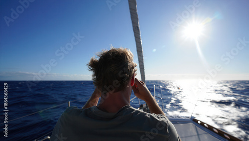 Young Man Looking Through Binoculars on Sailing Yacht in Open Sea