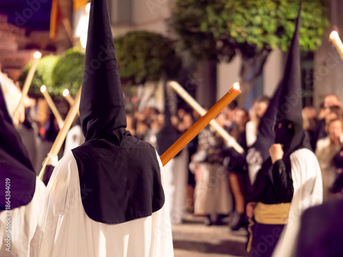 Tableau sur toile Nazarenes in white tunics and black hoods walking in a night procession with candles
