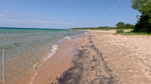 Reverse motion walking on the beautiful beaches of Lake Michigan. Pure, clear transparent waves roll onto the shore. Unspoiled nature located within Wilderness State Park in Northern Michigan, USA. 