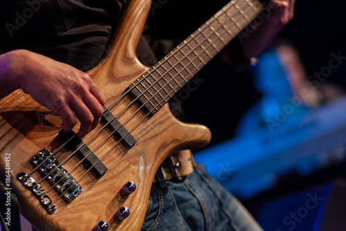 Close-up of bassist playing natural wood grain bass guitar during live performance