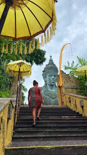 Woman ascending stairs towards statue in Bali