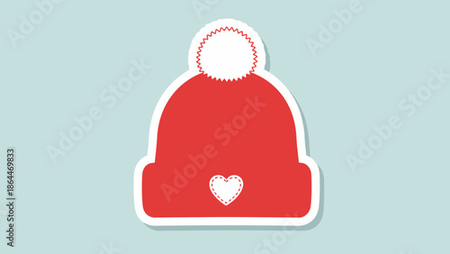 Red Winter Beanie Hat with White Pom Pom and Heart Detail, Isolated on Light Blue