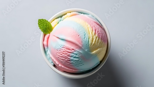 A delicious scoop of rainbow ice cream with a mint leaf on top, presented in a white bowl.