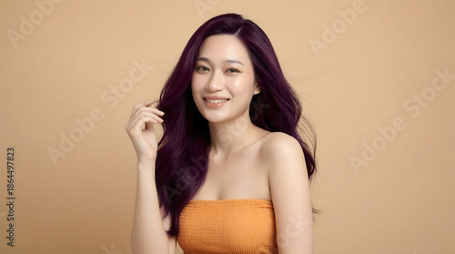 Wallpaper Mural Smiling young Asian woman with vibrant dark purple hair, wearing an orange strapless top, posing against a plain background. Torontodigital.ca