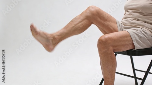 Wallpaper Mural elderly Man sitting on folding chair lifting one bare leg, active aging concept Torontodigital.ca