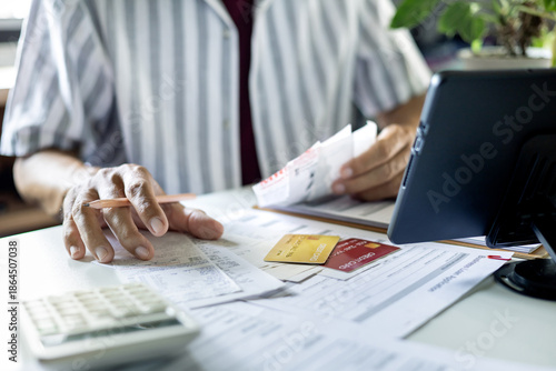 Foto asian man checking receipts and financial bills calculate expenses from credit c