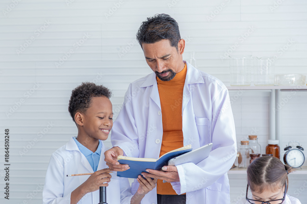 Obraz premium Group of multicultural students in lab coat uniform studying with Indian teacher writing report in laboratory, pupils boy and girls scientist having fun in science class with microscope and test tube