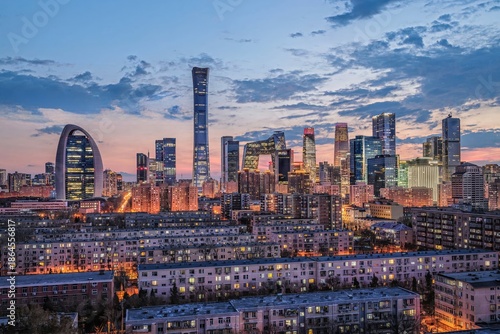 Night view of Beijing CBD skyline with modern skyscrapers and illuminated buildings during blue hour, showing urban development and city life.
