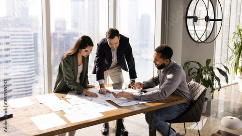 Foto African American manager presenting project to investors, showing paper sales reports on meeting table, explaining marketing research results, discussing business plan