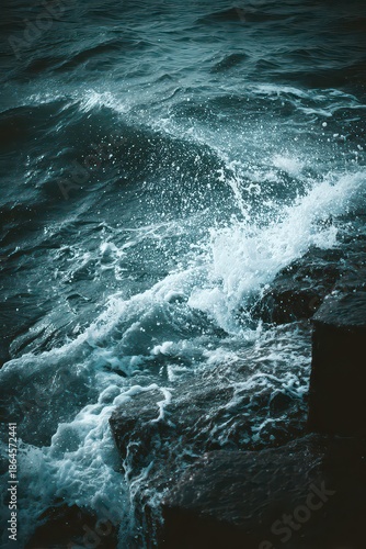 Ocean Waves Crashing Against Dark Rocks in Turquoise Water During Daytime with Foam and Splashes for Texture and Coastal Scenery