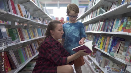 Little boy in glasses and his mother are choosing book