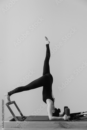 Black and white photo of woman training on Pilates reformer machine