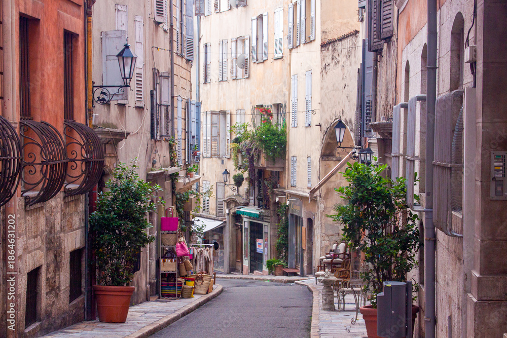 Fototapeta premium Narrow Mediterranean alley lined with stone buildings, small shops, and traditional architecture, capturing authentic daily life in a historic European town.