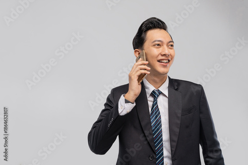 Asian executive on phone smiling confidently, engaged in business call mobile communication scene with striped tie, attentive