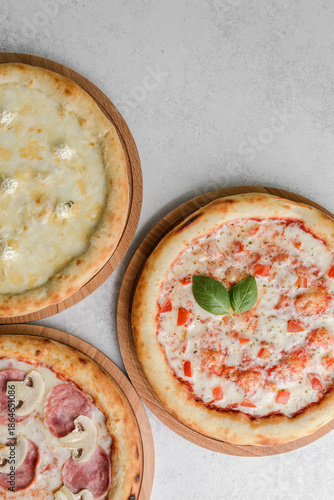 three different round pizzas on a grey background