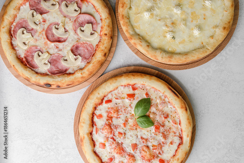 three different round pizzas on a grey background