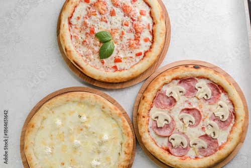three different round pizzas on a grey background