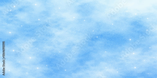 A beautiful blue winter sky background features bright white fluffy clouds and falling snowflakes in a clear natural light