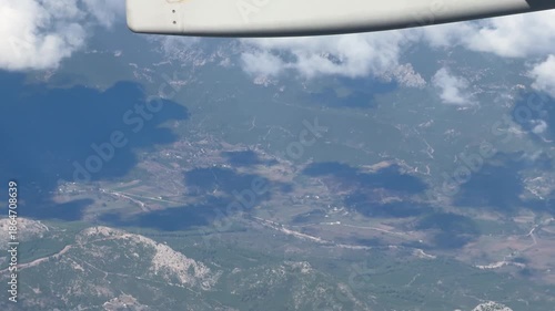 A passenger’s view from a plane flying above breathtaking mountains—first focusing on the wing, then gazing down at the stunning landscape below.