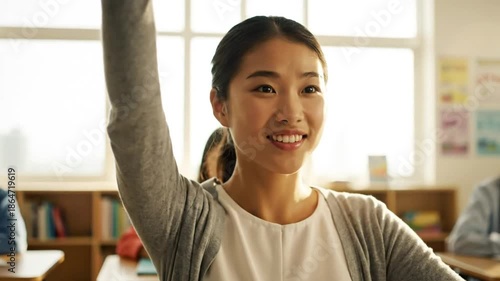 Enthusiastic student raising her hand in bright classroom setting, ready to participate and answer questions