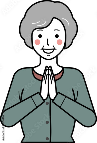 正面向き。いただきますと手を合わせるカーディガンを着た高齢女性。