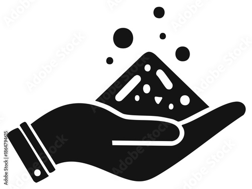 Hand holding a pile of granular material with small particles floating upwards