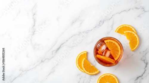Refreshing orange cocktail with ice and sliced orange on a white marble surface. Summer drink concept for beverage advertisement.