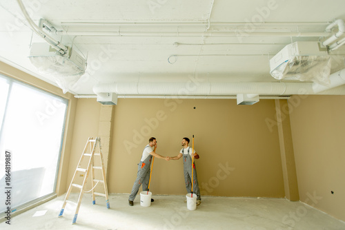 Two workers painting a wall...