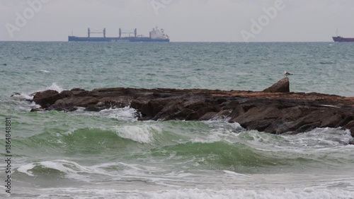 Stormy ocean waves crashing on rocky breakwater with seagull