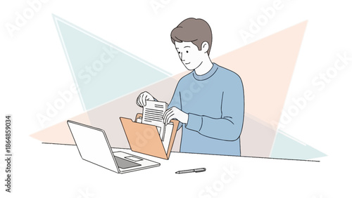 Young man organizing documents into a folder while working at his desk with a laptop and pen in an
