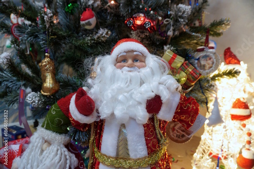 A Santa Claus toy on the background of a Christmas tree.