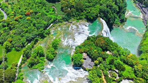 Wallpaper Mural The famous Huangguoshu Waterfall natural landscape in Guizhou, China. Aerial shot of a majestic waterfall cascading into a green river surrounded by lush forest in summer. Torontodigital.ca