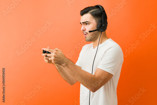 Quadro em tela Profile view of a man concentrating on playing video game with controller and he
