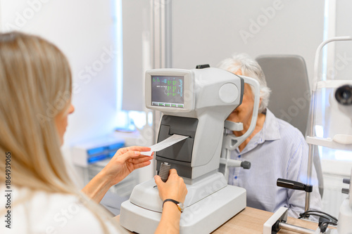 Εκτύπωση καμβά Female ophthalmologist checking slit lamp results while examining senior woman e