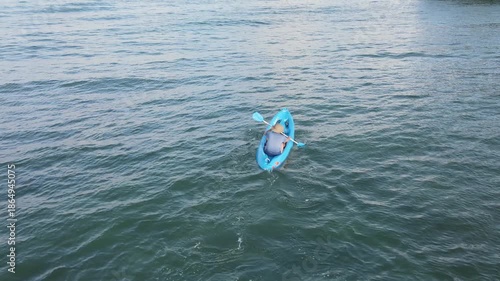 Aerial drone view of single kayak floating on calm open blue sea wide