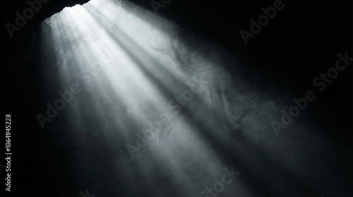 Dramatic volumetric white light beams or God rays shining through darkness with smoke and floating dust particles