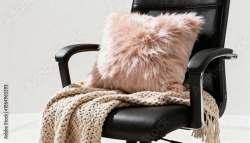 A black office chair with a pink and white blanket draped over it. The chair is empty and the blanket is covering the entire seat