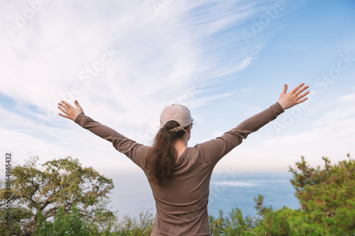 Woman celebrates freedom and success overlooking ocean horizon