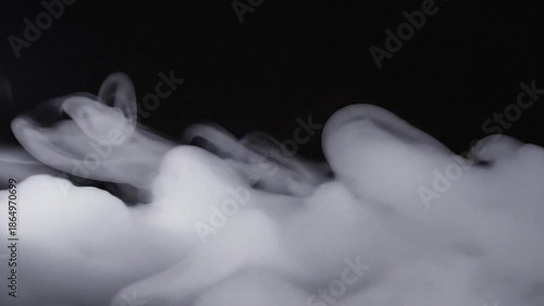 Thick white smoke flowing and spreading across a black background, creating an ethereal and mysterious atmosphere.