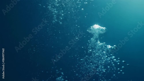 Underwater bubbles rising in clear blue water.