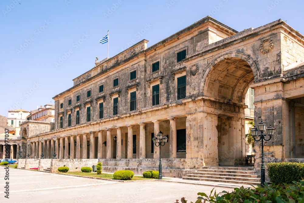 Fototapeta premium Historic neoclassical Palace of St. Michael and St. George in Corfu, Greece. A greek flag waving on the roof, clear blue sky